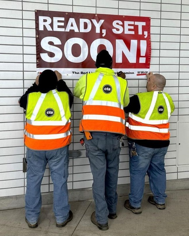 Three uniformed CTA employees are shown installing a large RLE banner emblazoned with the slogan "Ready, Set, Soon!" onto the wall at a CTA station